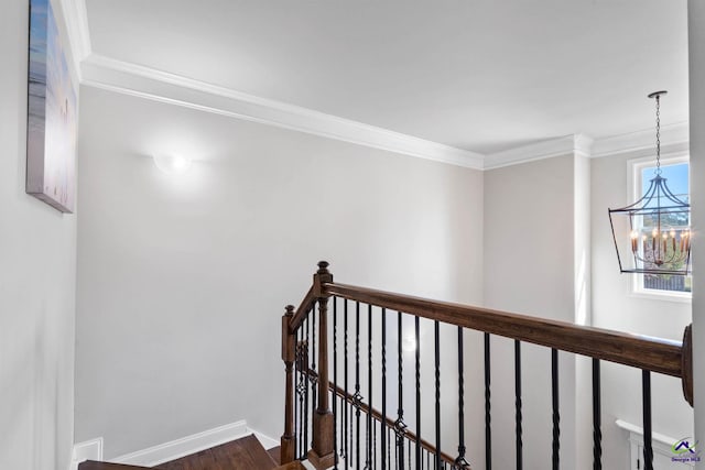 hall with a notable chandelier, dark wood-style flooring, an upstairs landing, baseboards, and crown molding