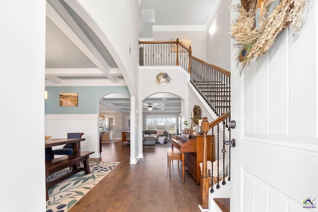 foyer entrance with arched walkways, beam ceiling, coffered ceiling, and wood finished floors