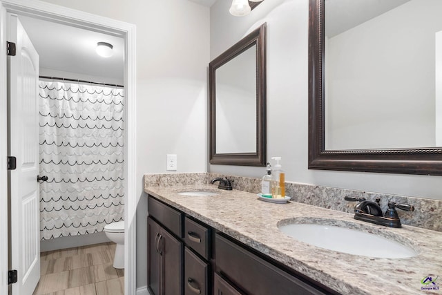 full bath with toilet, double vanity, a sink, and a shower with shower curtain