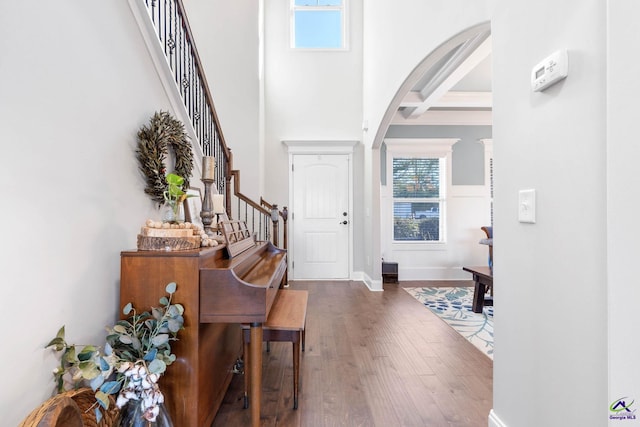 entryway featuring arched walkways, coffered ceiling, stairway, wood finished floors, and beamed ceiling