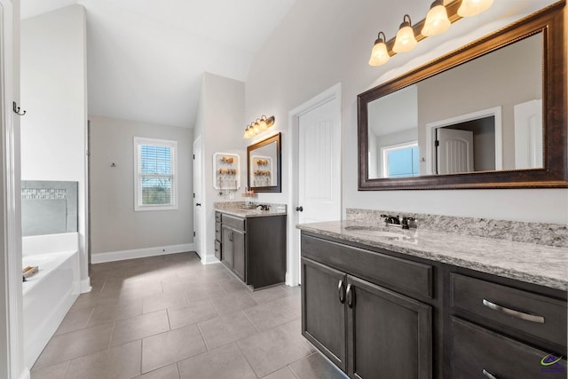 bathroom with lofted ceiling, two vanities, a sink, tile patterned flooring, and a bath