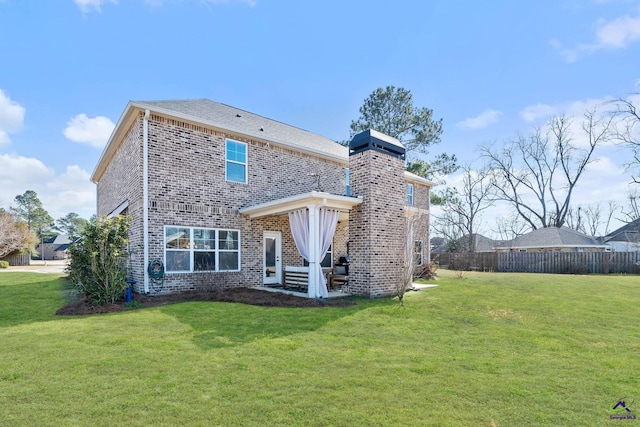 rear view of house featuring a yard, brick siding, and fence