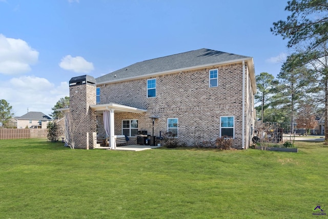 rear view of property with a patio, a chimney, fence, a yard, and brick siding