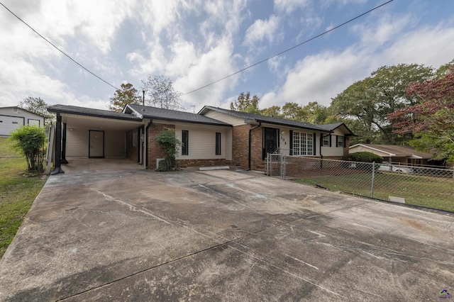 single story home featuring driveway, brick siding, fence, and an attached carport