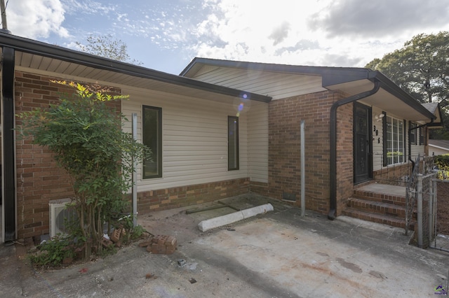 view of property exterior with a patio and brick siding