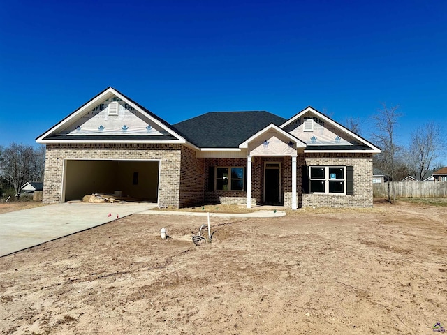 view of front of house with a garage, driveway, fence, and brick siding