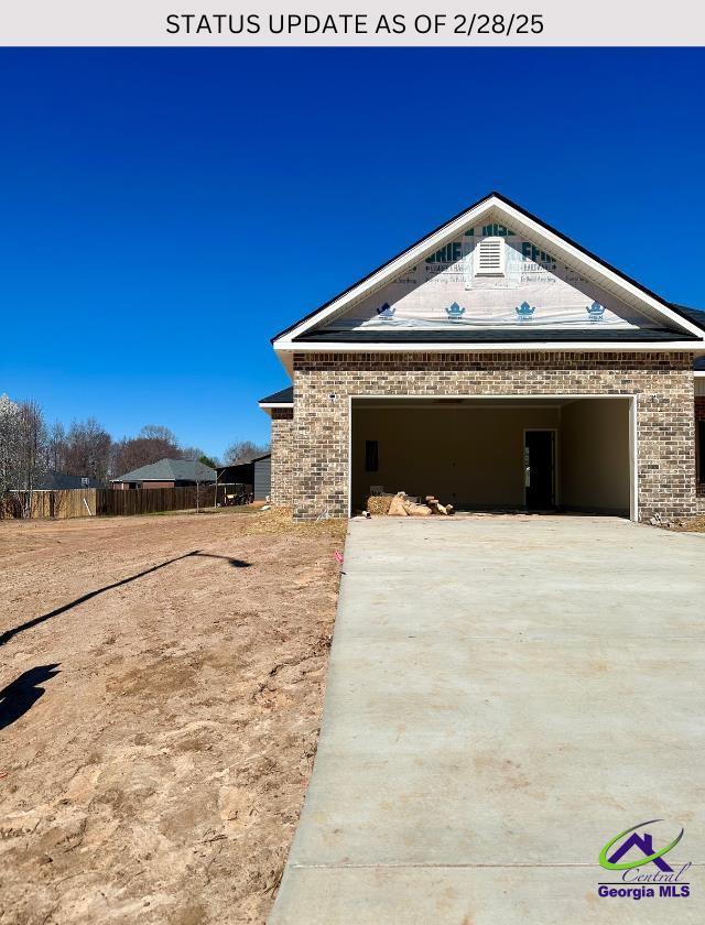 102 Reedy Ct, Perry, GA 31069 - view of side of property featuring concrete driveway, brick siding, an attached garage, and fence