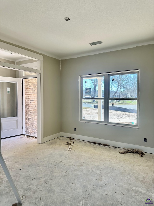 unfurnished room featuring a textured ceiling, plenty of natural light, and baseboards