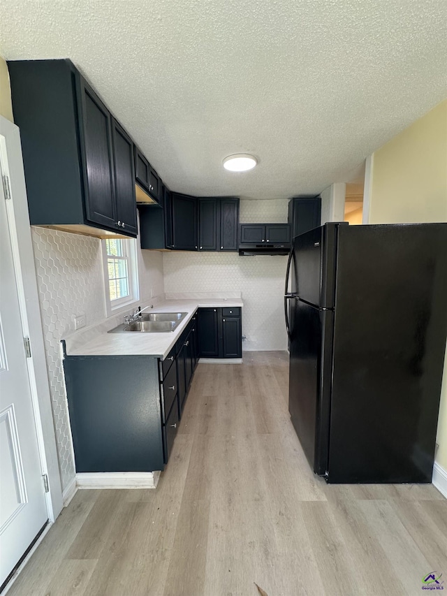 kitchen featuring light wood-type flooring, a sink, and freestanding refrigerator