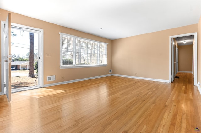 unfurnished living room with a healthy amount of sunlight, visible vents, light wood-style flooring, and baseboards