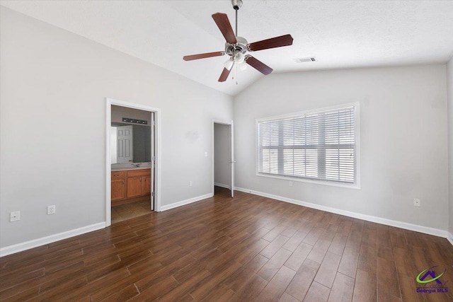 unfurnished bedroom with dark wood-style floors, visible vents, vaulted ceiling, and baseboards