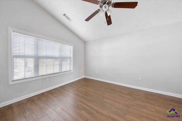 spare room featuring dark wood-style floors, lofted ceiling, visible vents, a ceiling fan, and baseboards