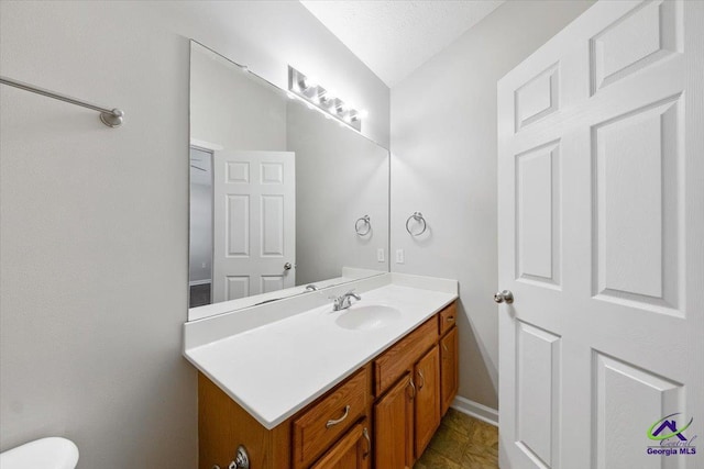 half bathroom featuring toilet, vanity, and baseboards