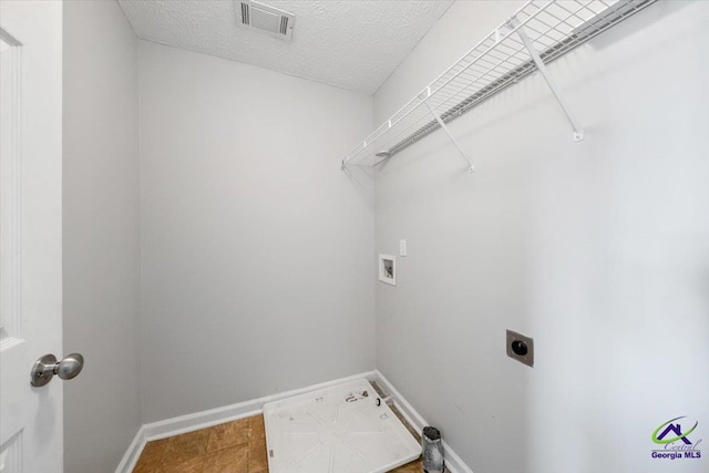 washroom featuring visible vents, hookup for an electric dryer, a textured ceiling, laundry area, and baseboards