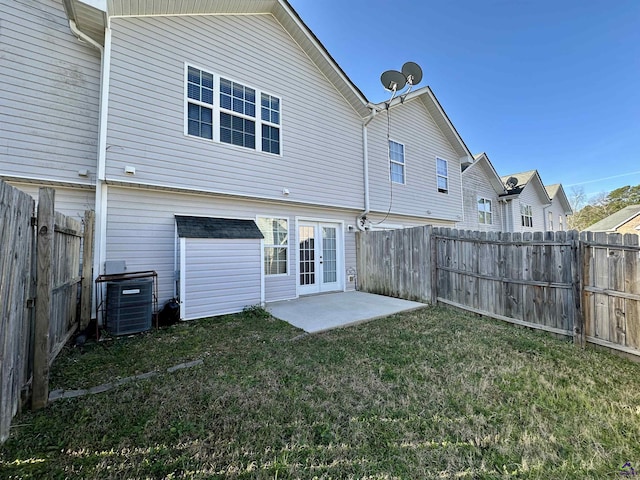 rear view of house featuring french doors, a yard, a patio, central AC unit, and a fenced backyard