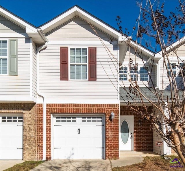 townhome / multi-family property featuring a garage, concrete driveway, and brick siding