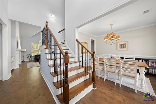 stairway featuring a notable chandelier, wood finished floors, visible vents, baseboards, and crown molding