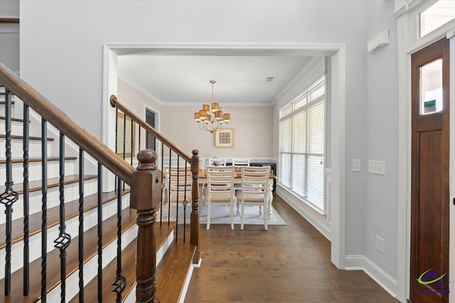 entrance foyer with a chandelier, dark wood-style flooring, ornamental molding, and stairs