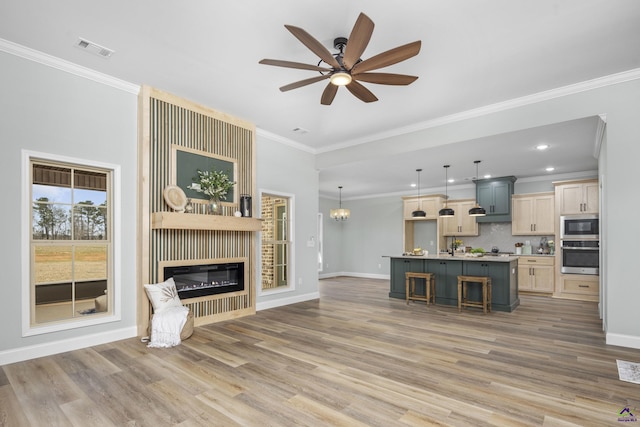 unfurnished living room featuring baseboards, visible vents, light wood-style flooring, crown molding, and a fireplace