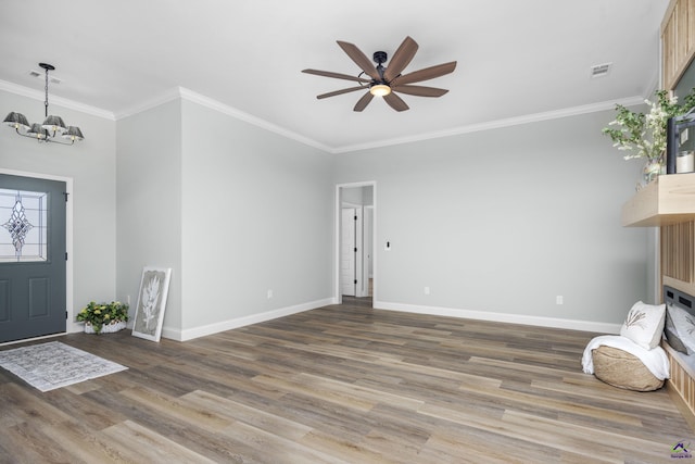 foyer featuring ceiling fan with notable chandelier, wood finished floors, visible vents, baseboards, and ornamental molding