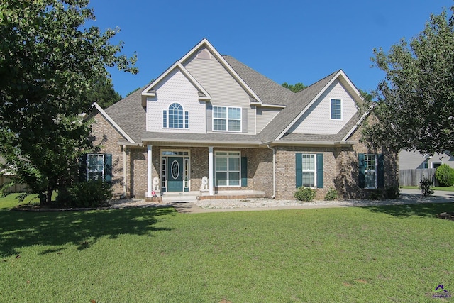 craftsman inspired home featuring brick siding, a shingled roof, fence, and a front yard