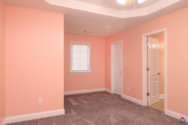 empty room with carpet, visible vents, and baseboards