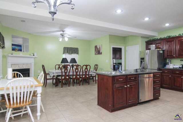 kitchen with a fireplace, dark countertops, appliances with stainless steel finishes, a ceiling fan, and dark brown cabinets