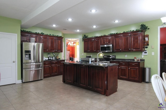 kitchen with a center island with sink, dark countertops, stainless steel appliances, a sink, and recessed lighting