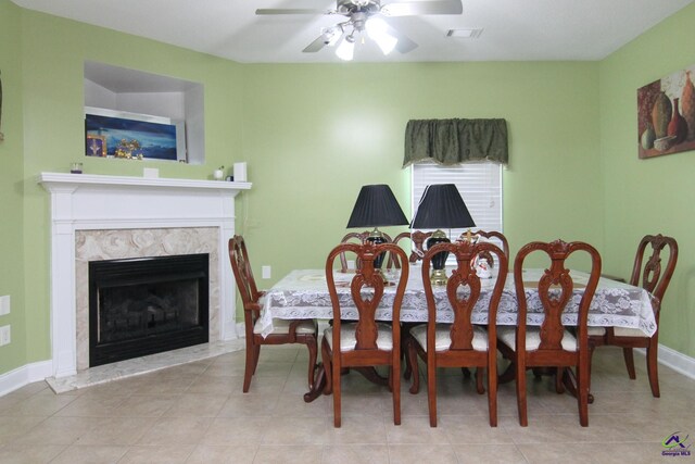 dining space with baseboards, a premium fireplace, visible vents, and a ceiling fan
