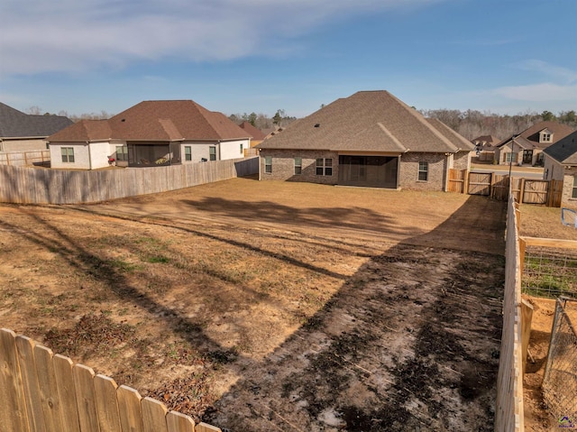 view of yard featuring a fenced backyard, a residential view, and a gate