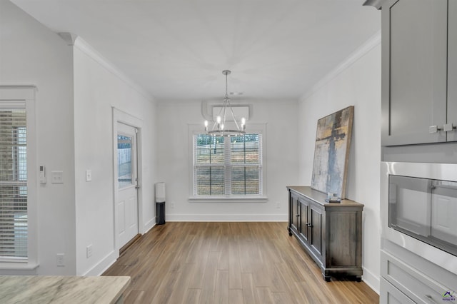 dining room with baseboards, light wood-type flooring, an inviting chandelier, and crown molding