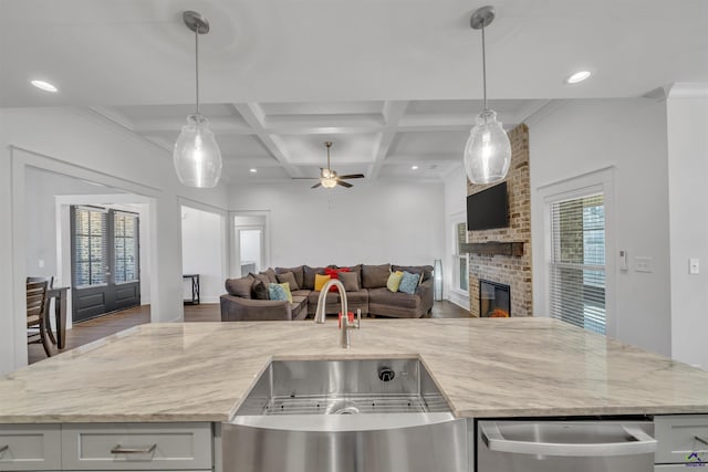 kitchen featuring light stone counters, beam ceiling, a brick fireplace, open floor plan, and coffered ceiling