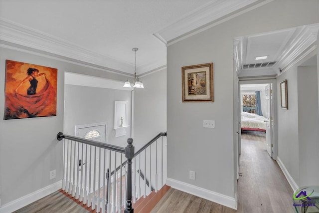 hallway featuring crown molding, visible vents, an upstairs landing, wood finished floors, and baseboards