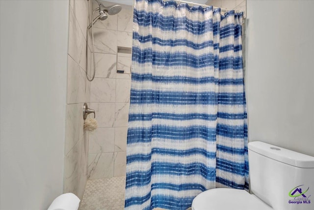 bathroom with a tile shower and toilet