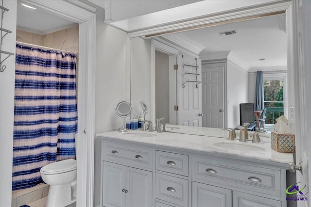 full bath with double vanity, ornamental molding, a sink, and toilet