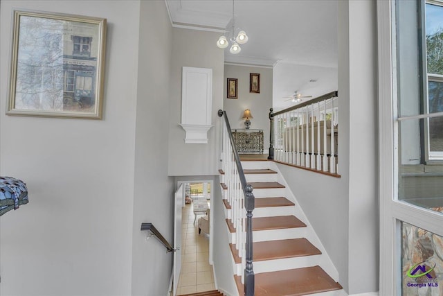 staircase featuring ornamental molding and a ceiling fan