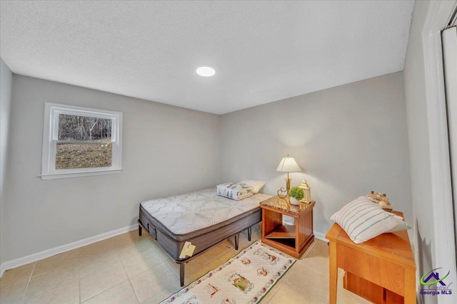 bedroom featuring a textured ceiling, baseboards, and light tile patterned floors