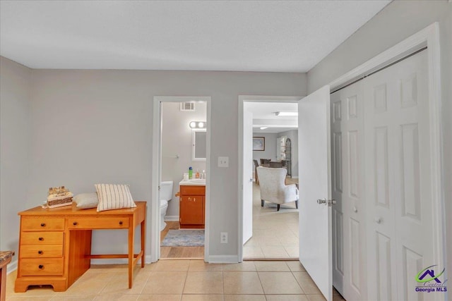 bedroom with light tile patterned floors, baseboards, visible vents, ensuite bathroom, and a closet