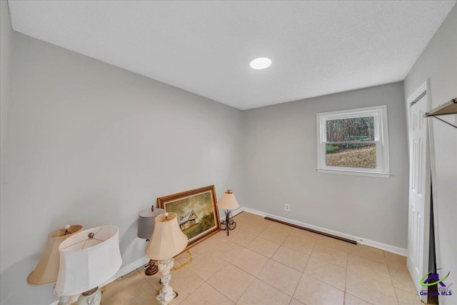 interior space with tile patterned flooring, a textured ceiling, and baseboards