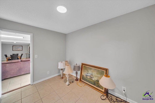 sitting room with a textured ceiling, light tile patterned flooring, and baseboards