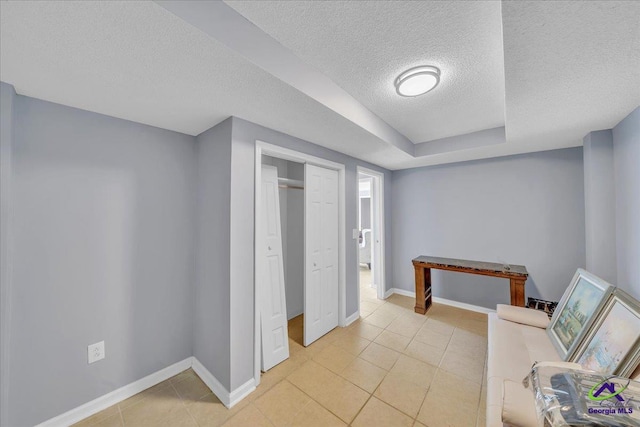 interior space with a closet, a textured ceiling, baseboards, and light tile patterned floors