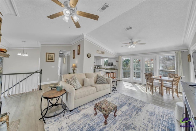 living area with light wood finished floors, visible vents, a textured ceiling, and ornamental molding