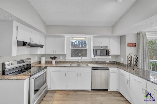 kitchen with light wood finished floors, appliances with stainless steel finishes, white cabinets, a sink, and under cabinet range hood