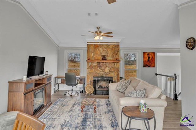 living area featuring crown molding, a fireplace, and wood finished floors