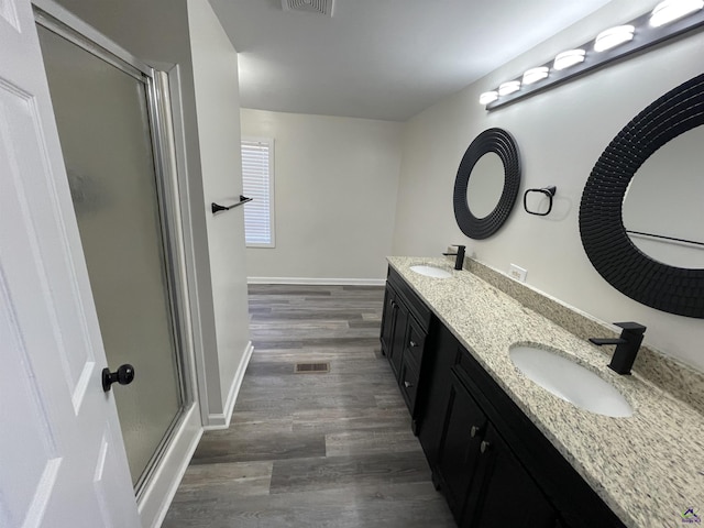 full bath featuring wood finished floors, a shower with shower door, a sink, and visible vents