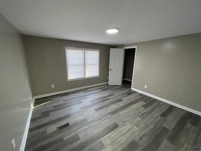 unfurnished bedroom with visible vents, baseboards, and dark wood finished floors