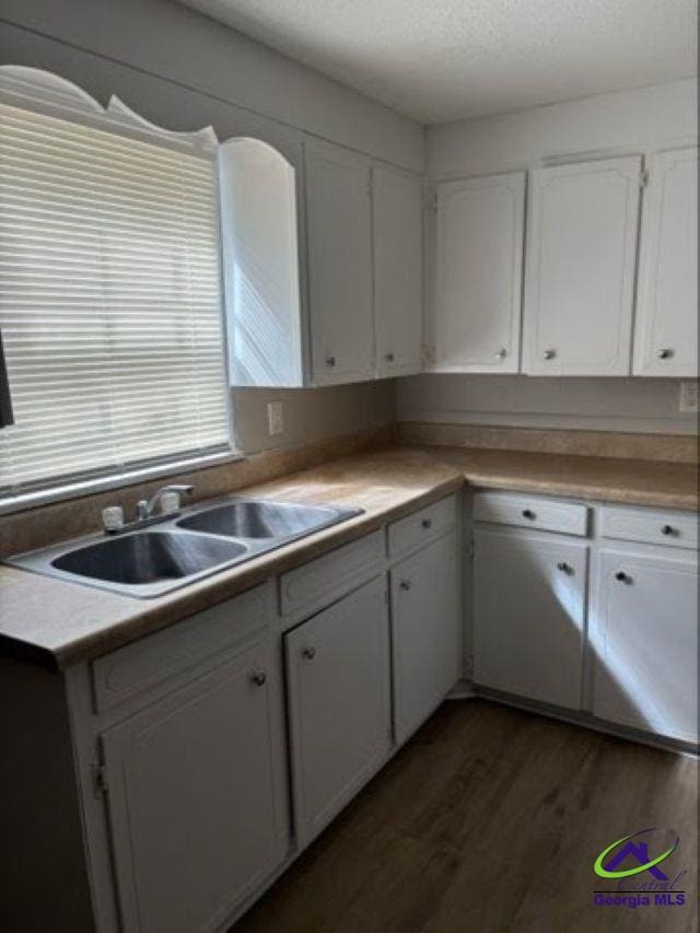 kitchen featuring a textured ceiling, a sink, white cabinets, light countertops, and dark wood-style floors