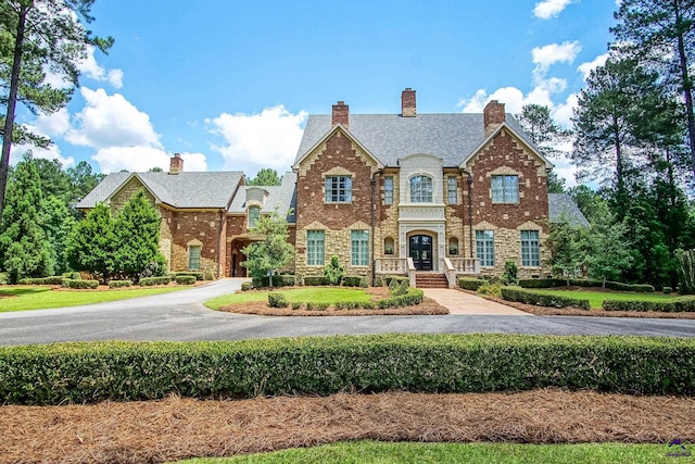 view of front of property with brick siding, a front yard, and aphalt driveway