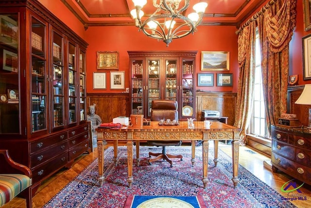 office area featuring wood finished floors, a wainscoted wall, crown molding, and an inviting chandelier