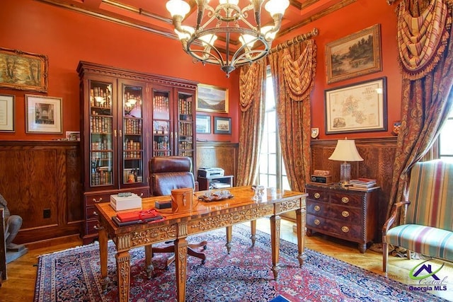 office space with wainscoting, wood finished floors, an inviting chandelier, and crown molding